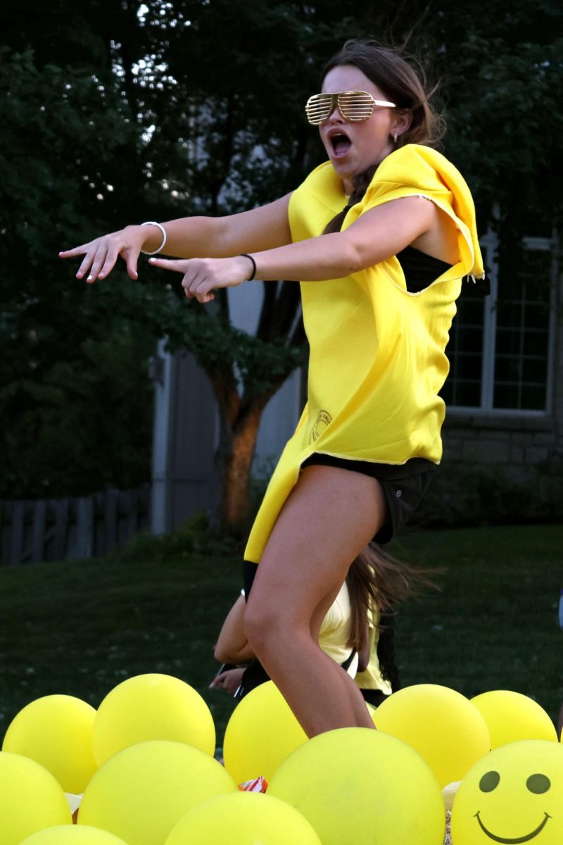 Wearing all yellow, freshman Ellie Newell, points to the crowd for cheers. 