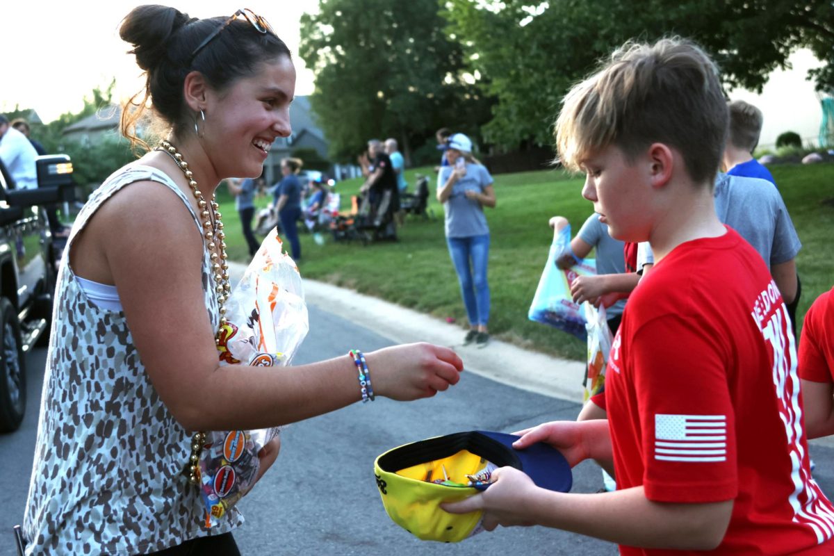 Walking alongside the choir float, freshman Lacey Jennings, gives candy to kids. 