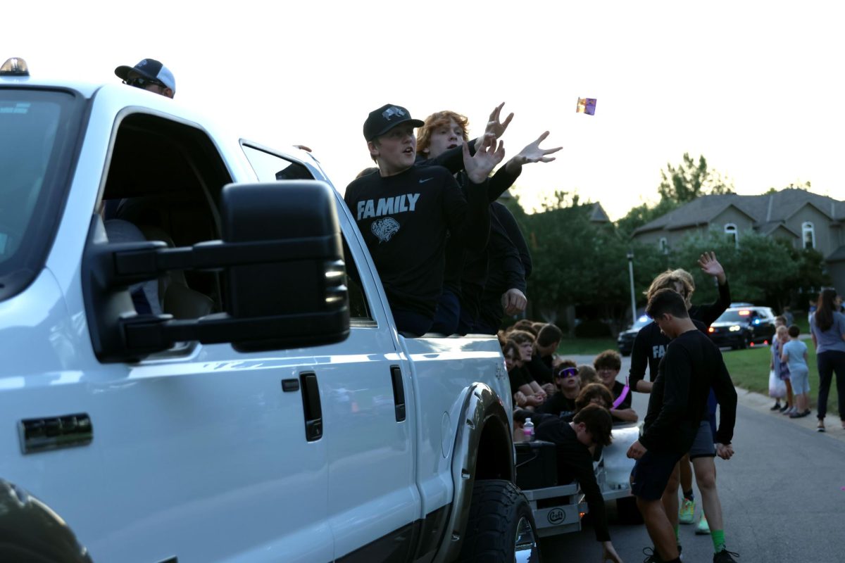 Riding on the back of their float, freshman football players catch candy thrown by the crowd. 