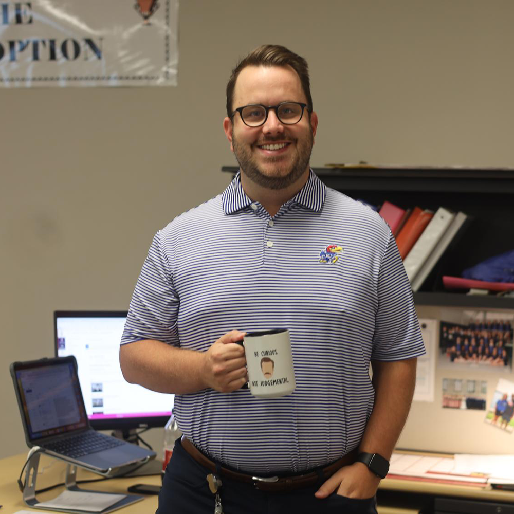 Business teacher Brain Kirkpatrick holds up his Ted Lasso mug that says “be curious, not judgmental,” Friday, Sep. 1. 