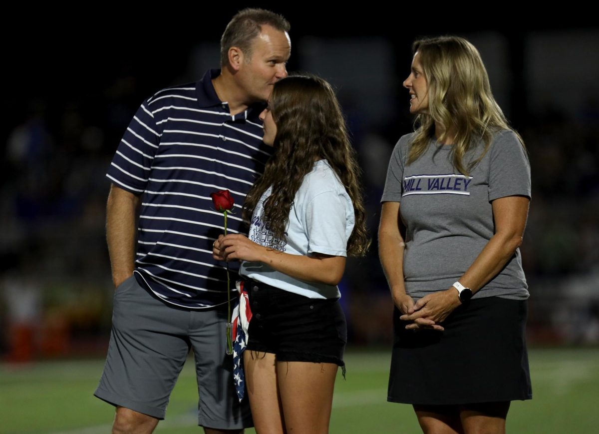 Dad of senior Ellie Walker whispers in her ear during the senior ceremony.