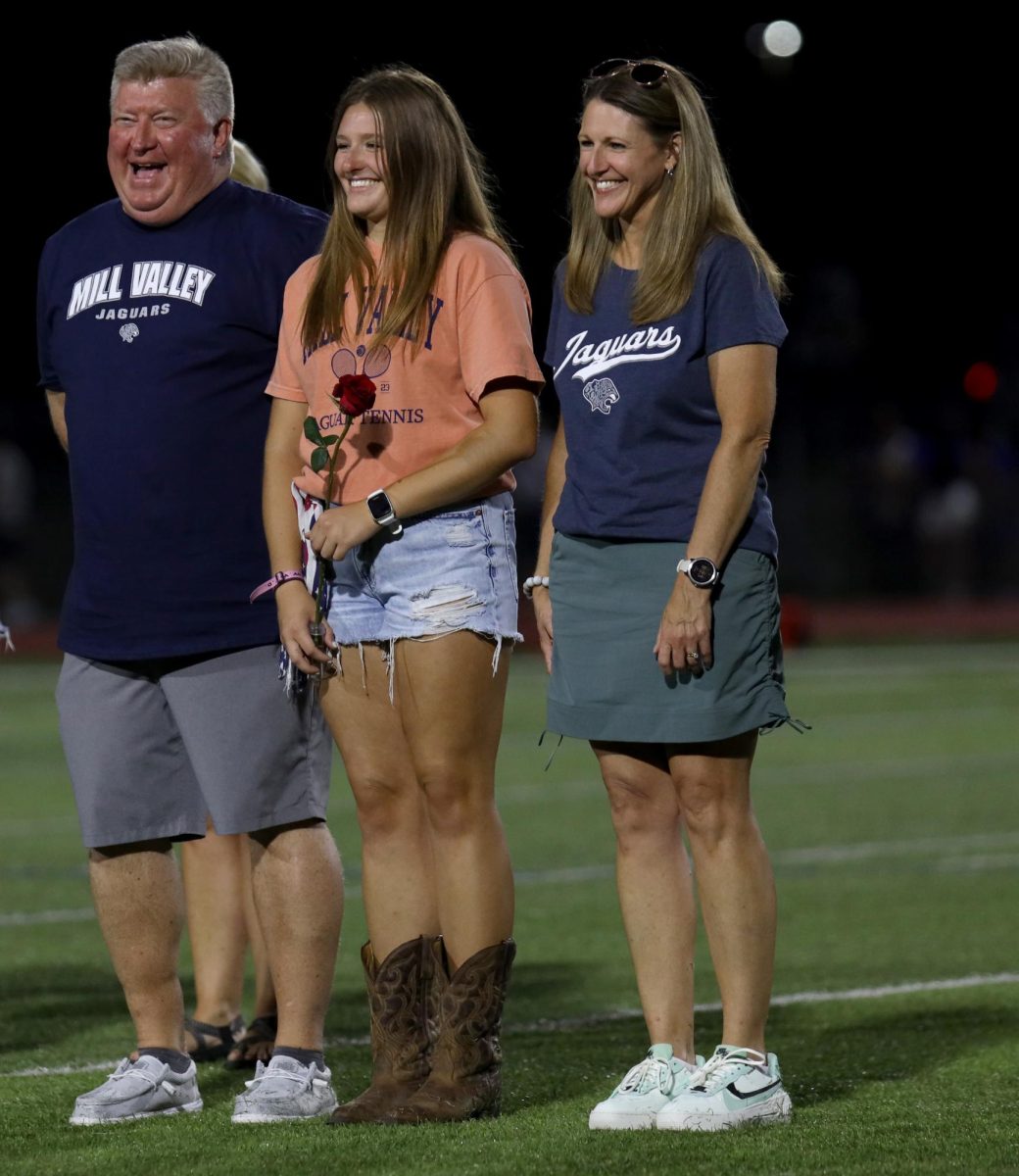 Senior Lucy Roy smiles with her parents during senior night.