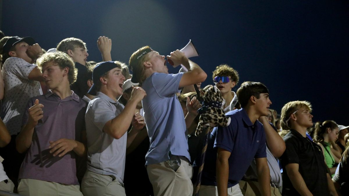 Senior Porter Slattery and Lucas Longhofer cheer for the Jaguars from the student section.
