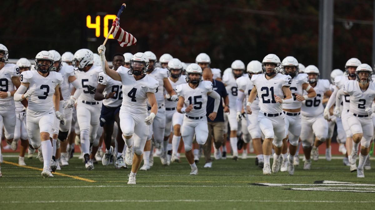 Senior Garrett Cronin leads the team on the field with an American flag. 

