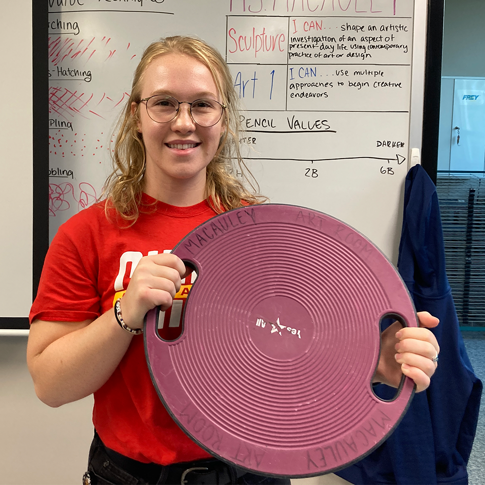 Art teacher Samantha MacAuley holds up her wobble board Tuesday, Sep. 5. I do have a wobble board in my classroom because I dont sit still very well, MacAuely said.