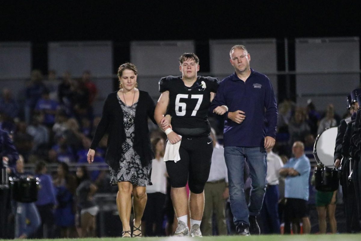 Senior Jack Fulcher walks with his parents after his name was called for coronation. 