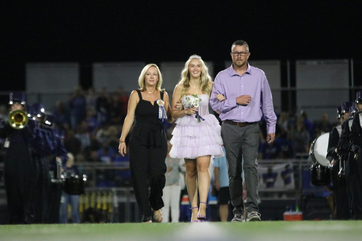 Flowers in hand, senior Olivia Moore smiles while walking with her parents.