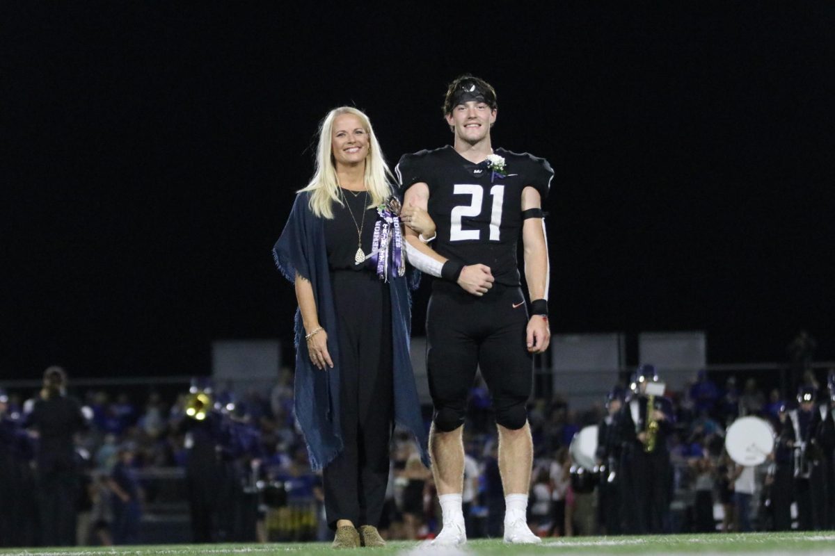 With their arms locked together, senior Tristan Baker smiles with his mom. 