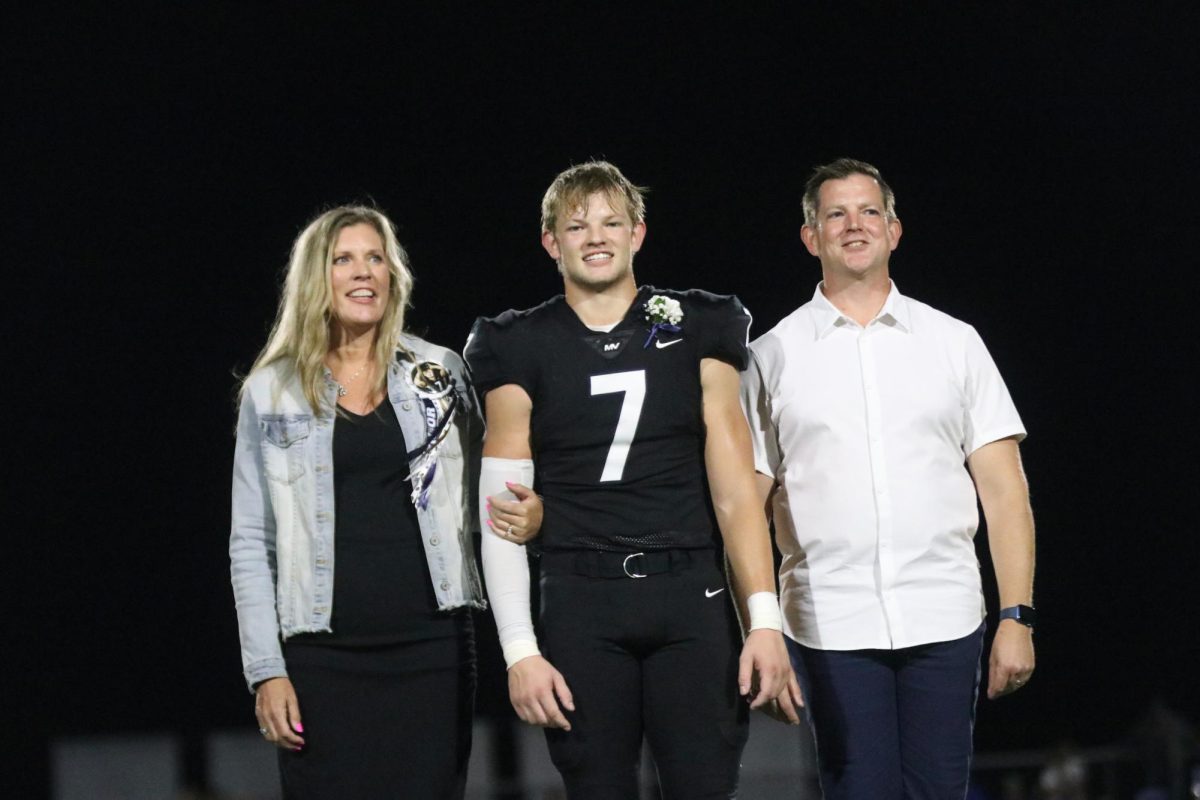 In full uniform, senior Preston Fischer smiles with his parents.