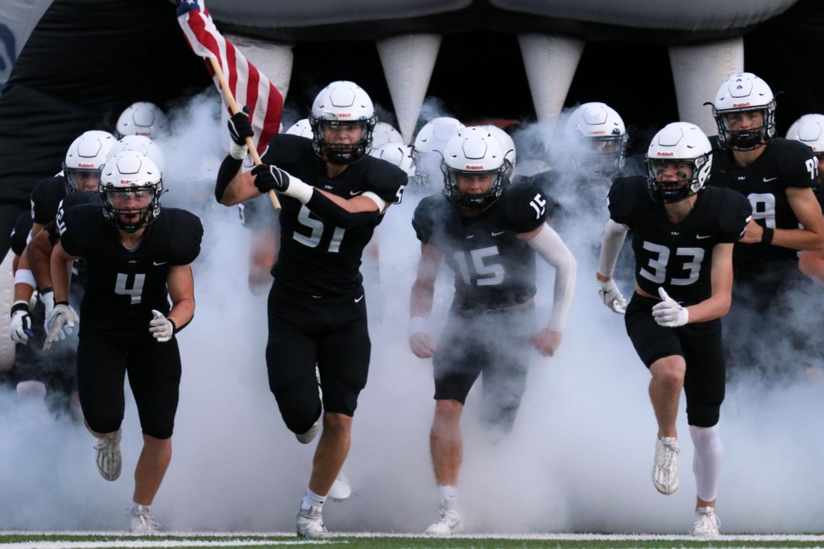 Senior Sam Colletti, carrying the American flag, leads the team through the smoke pregame. 