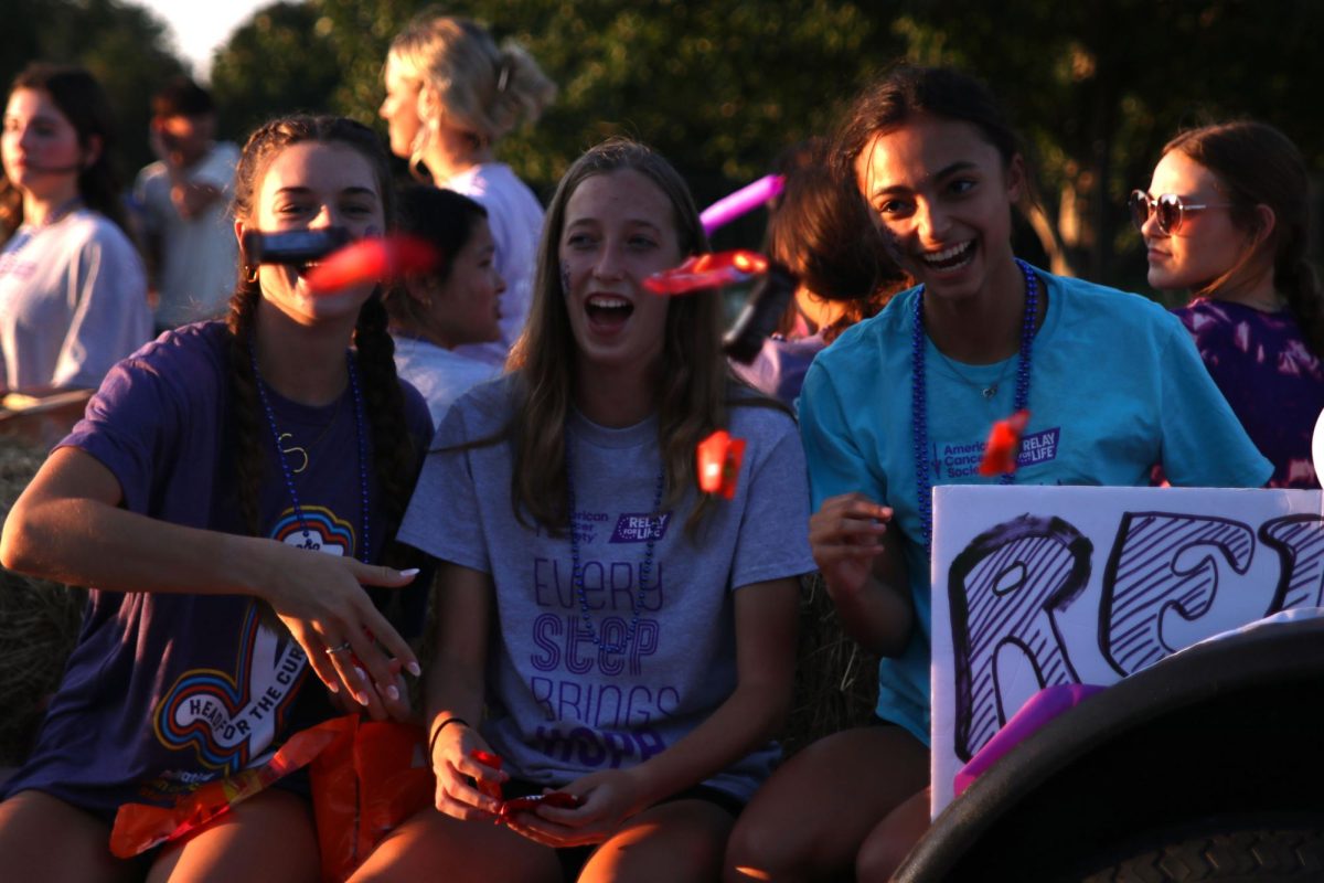 Laughing juniors Seville Skinner, Callie Cahoy, and Alonnah Gage throw candy while riding the Relay for Life float.
