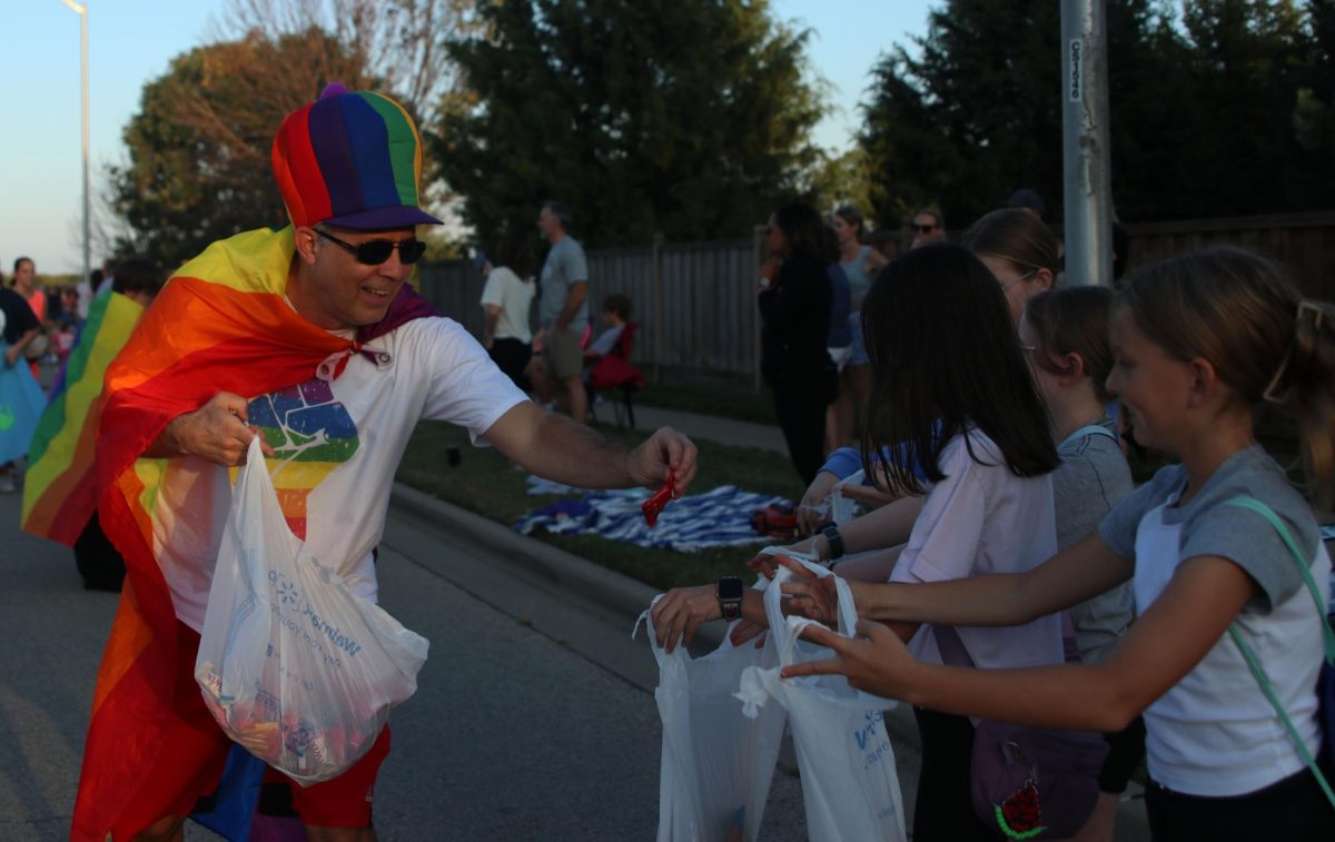 With a pride flag around his shoulders history teacher Jeff Wieland hands out candy.
