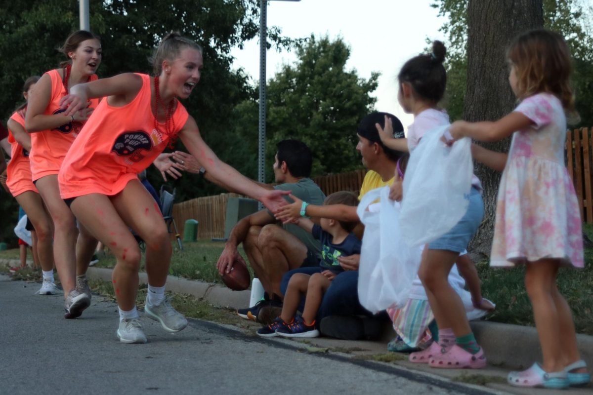 With her hand out junior Josie Benson high fives the kids watching the parade.