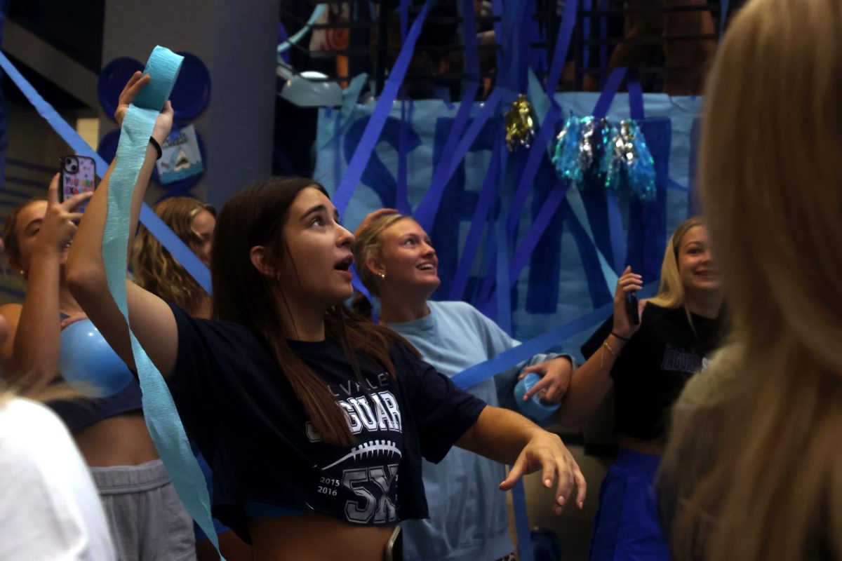 Looking up, senior Makenna Payne holds a roll of streamers. 
