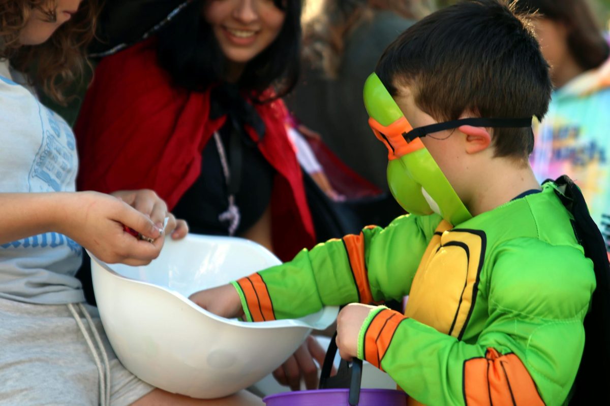 Dressed up as a Ninja Turtle, a KCIA student chooses candy from senior Katie Fredericks bowl.