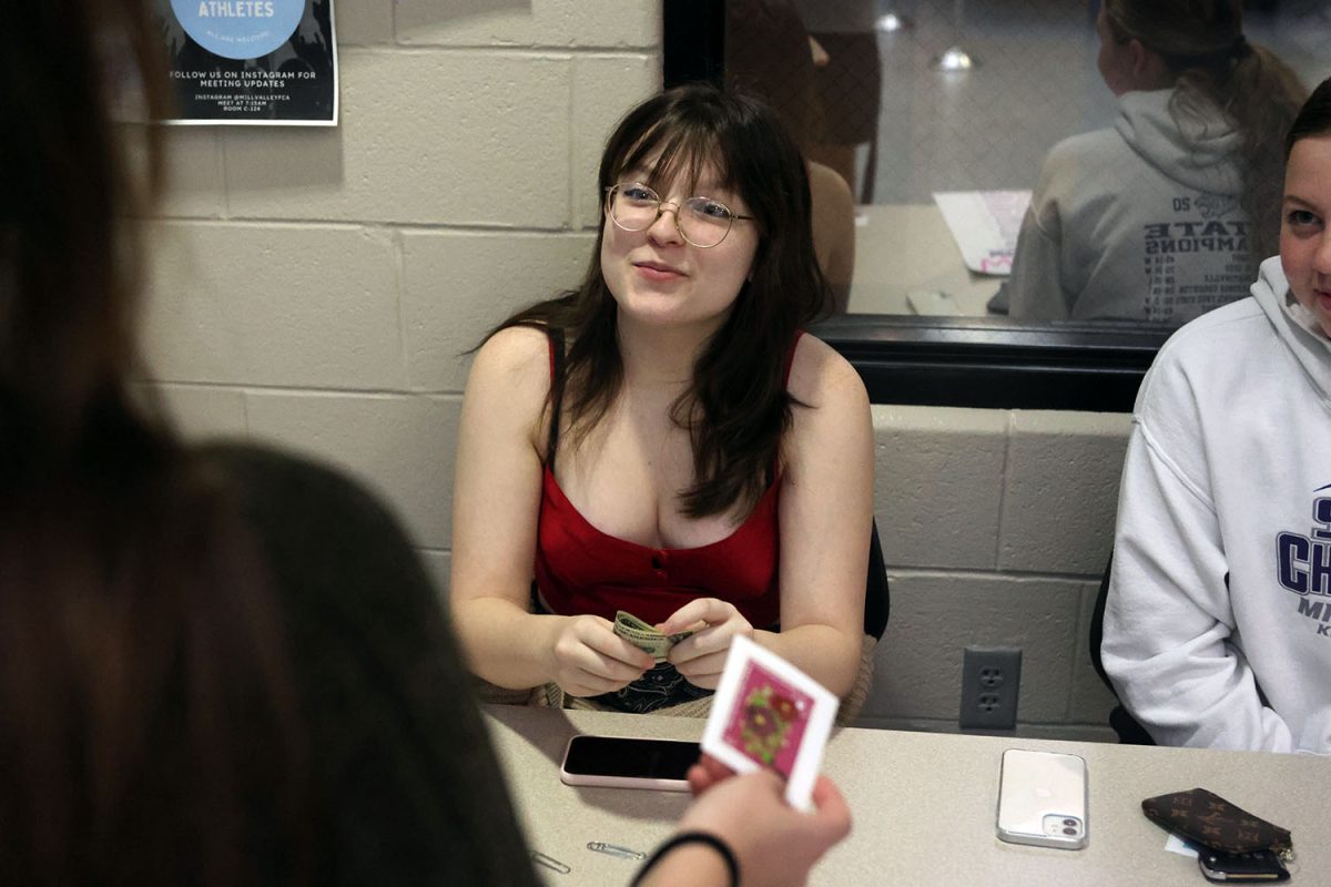 Taking donations for the Womens Empowerment Club fundraiser, senior Kaelyn Russell exchanges the cash for a club sticker. 