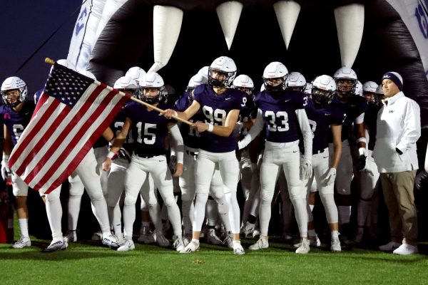Senior Kenten Laughman holds the American flag and leads the team out of the jaguar head. 