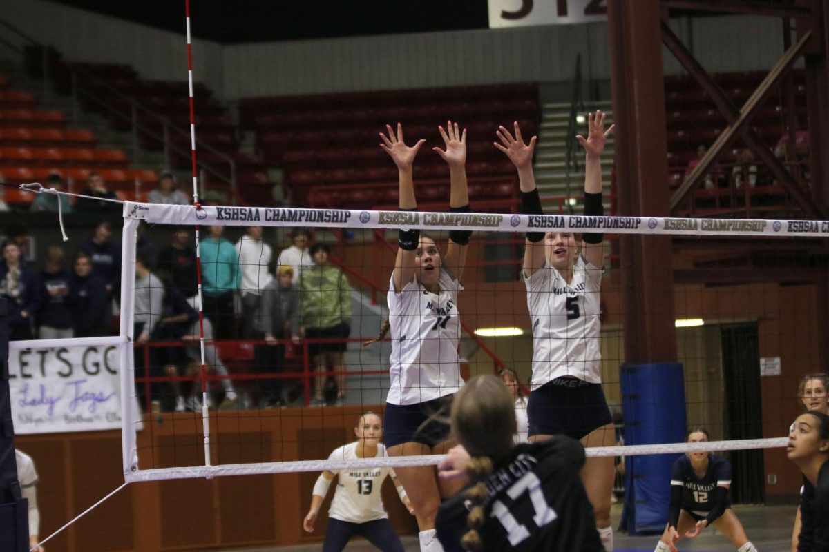 Arms up, sophomore Ella Florez and junior Saida Jacobs block a hit from Garden City.