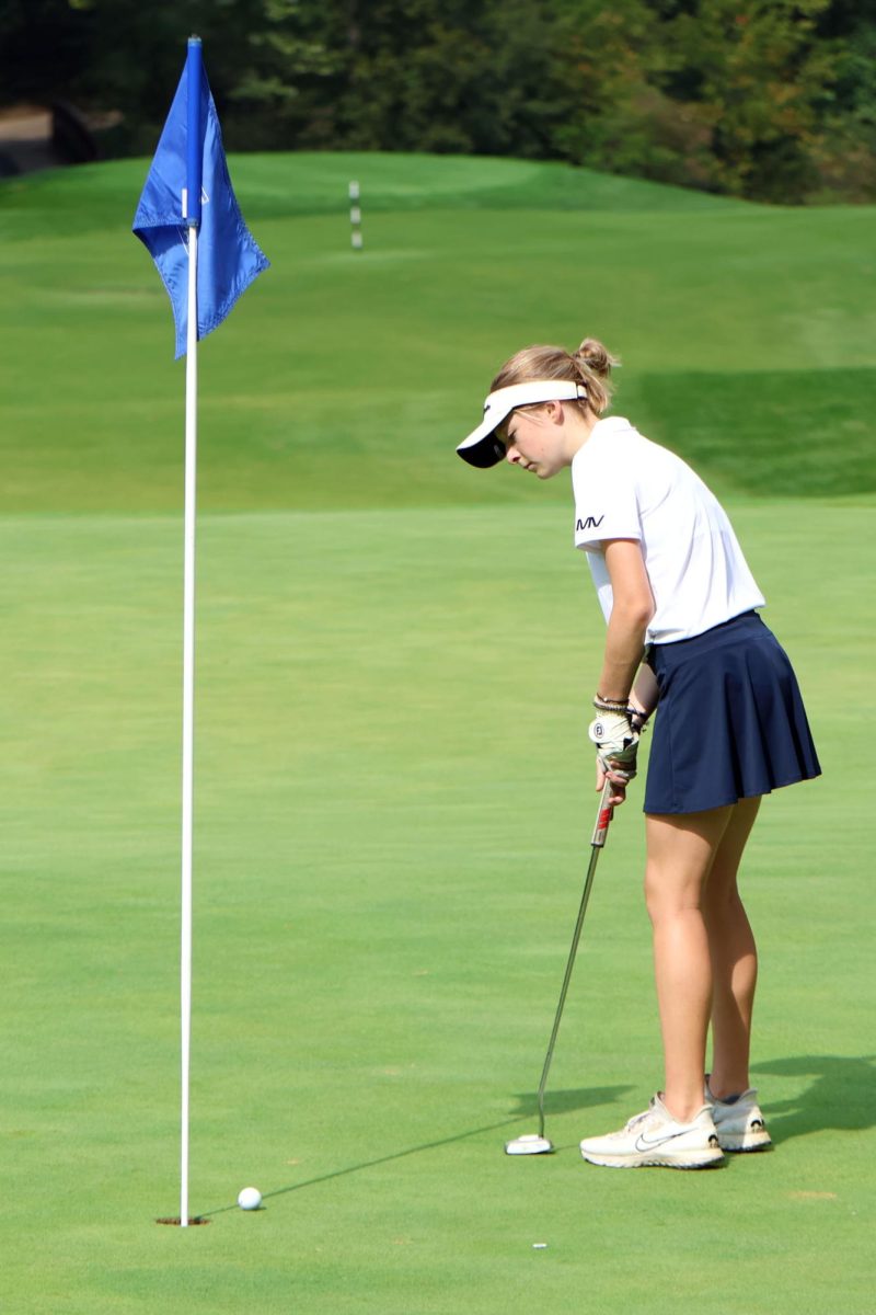 Focused on the ball, junior Regan Swartz puts the ball into the hole. 