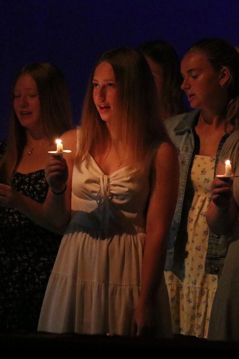 Holding a lit candle, junior Molly Barhost recites the Spanish National Honor Society oath to the president.