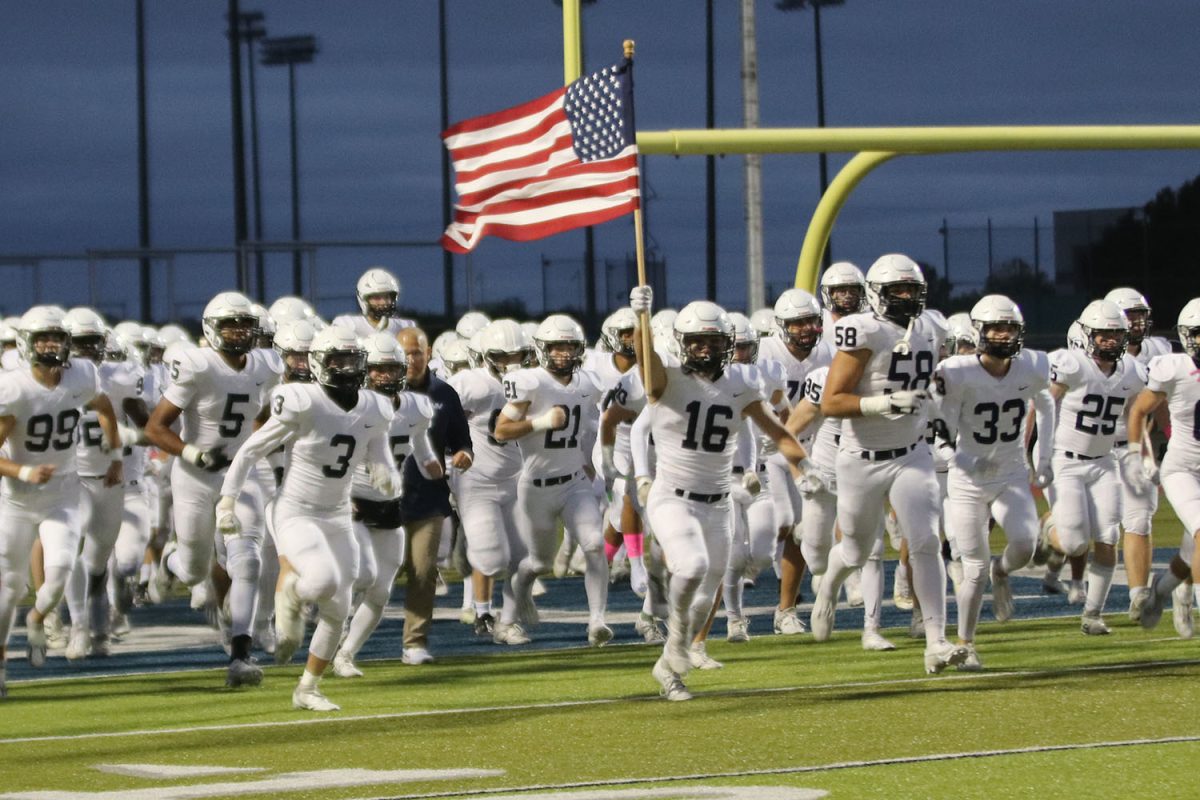 Carrying the flag, senior Ryan Deverill leads the team onto the field to start off the game.
