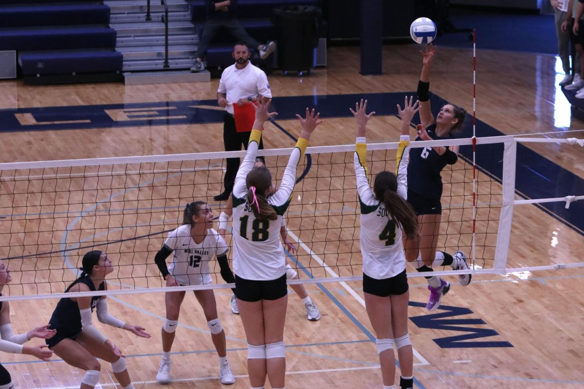 Reaching for the ball, senior Kaitlyn Burke looks to tip the ball over the opposing teams blockers for the point.