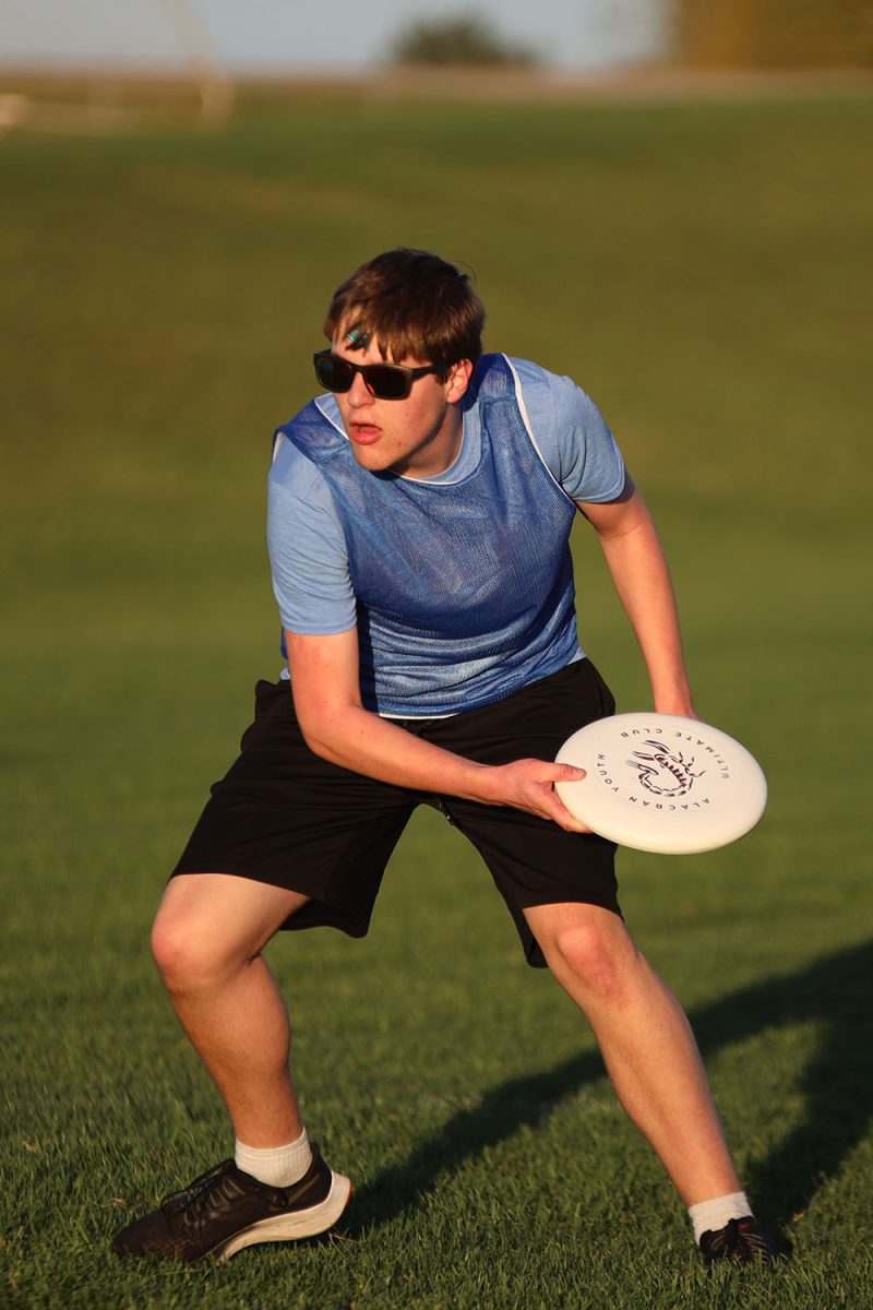 Warming up, sophomore Ian Weatherman throws the frisbee with his teammates. 