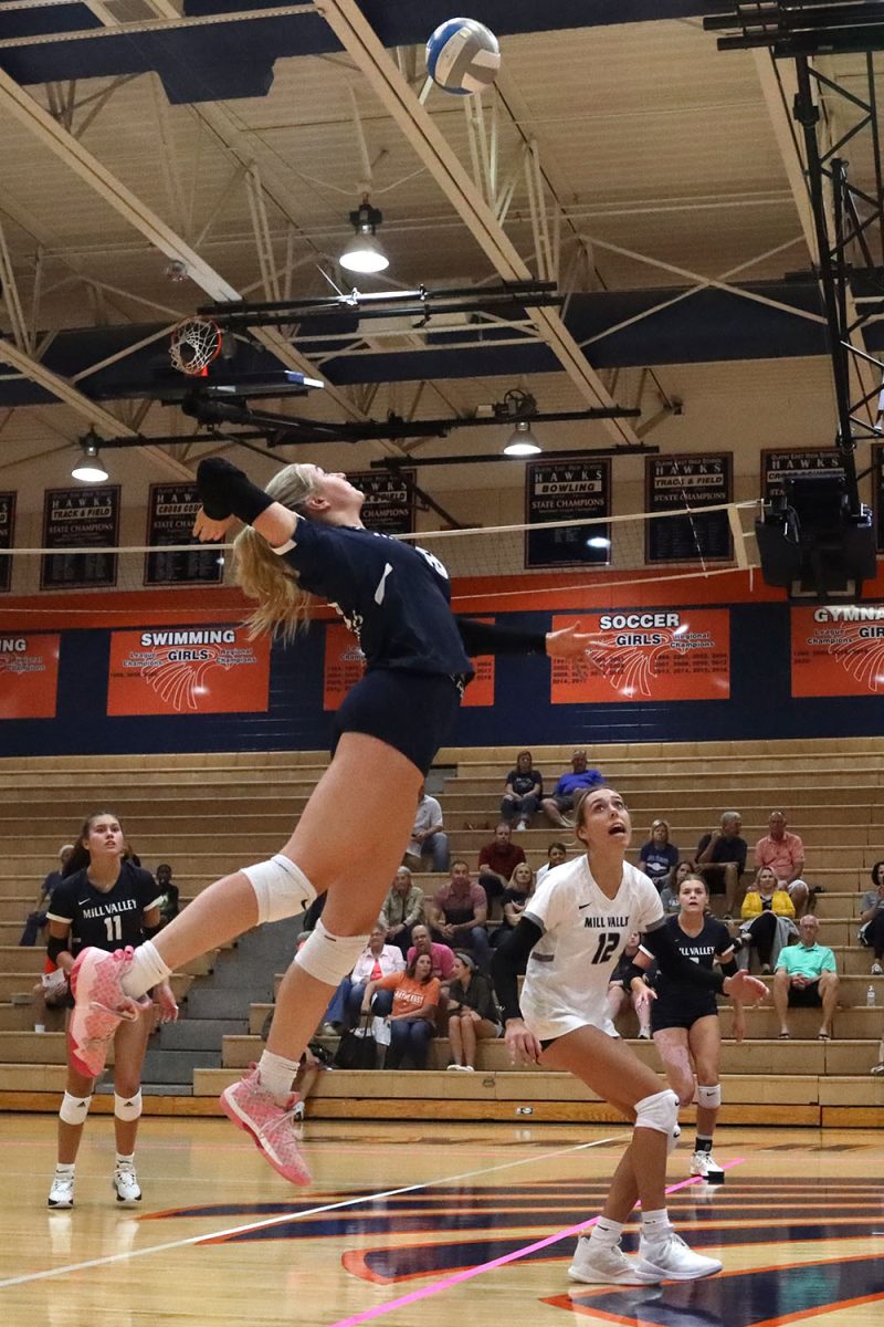 Jumping to make a spike, freshman Riley Riggs sends the ball over the net.