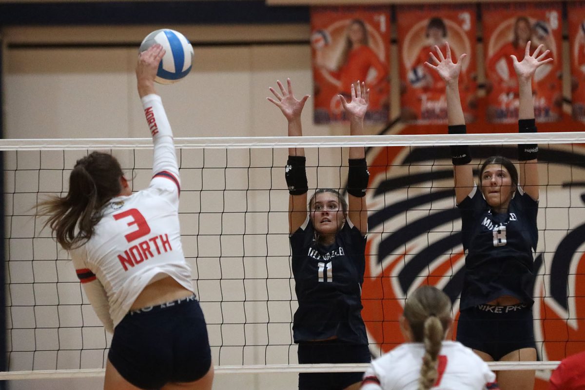 Jumping with their hands up, sophomore Ella Florez and junior Ashlyn Blazer block a spike.