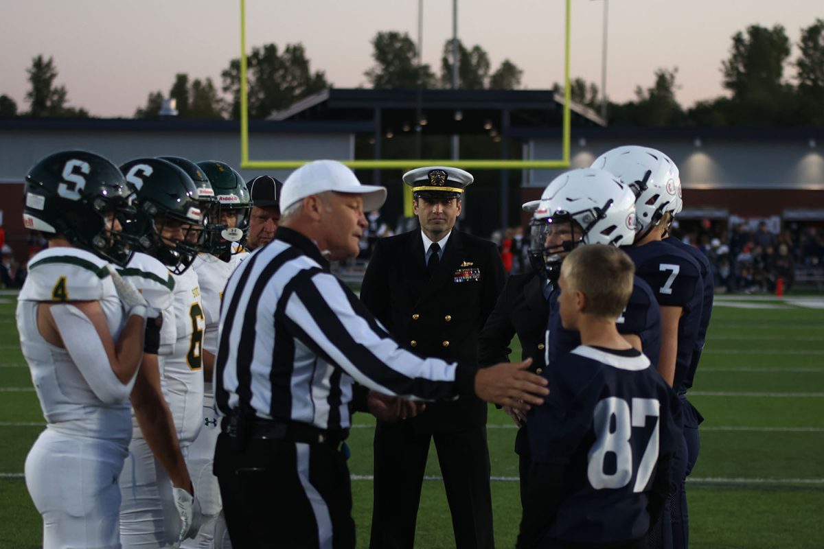 Overlooking the proceedings of the pre-game coin toss, Navy Lieutenant Commander Josh Bowling and Lieutenant Commander Russell Allen serve as honorary captains for Mill Valley.