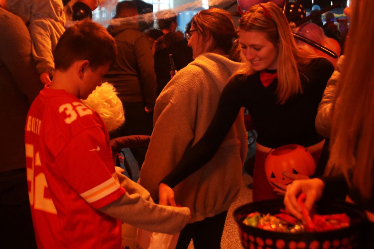 With a smile on her face, senior Audrey Holick greets kids by passing out candy. 
