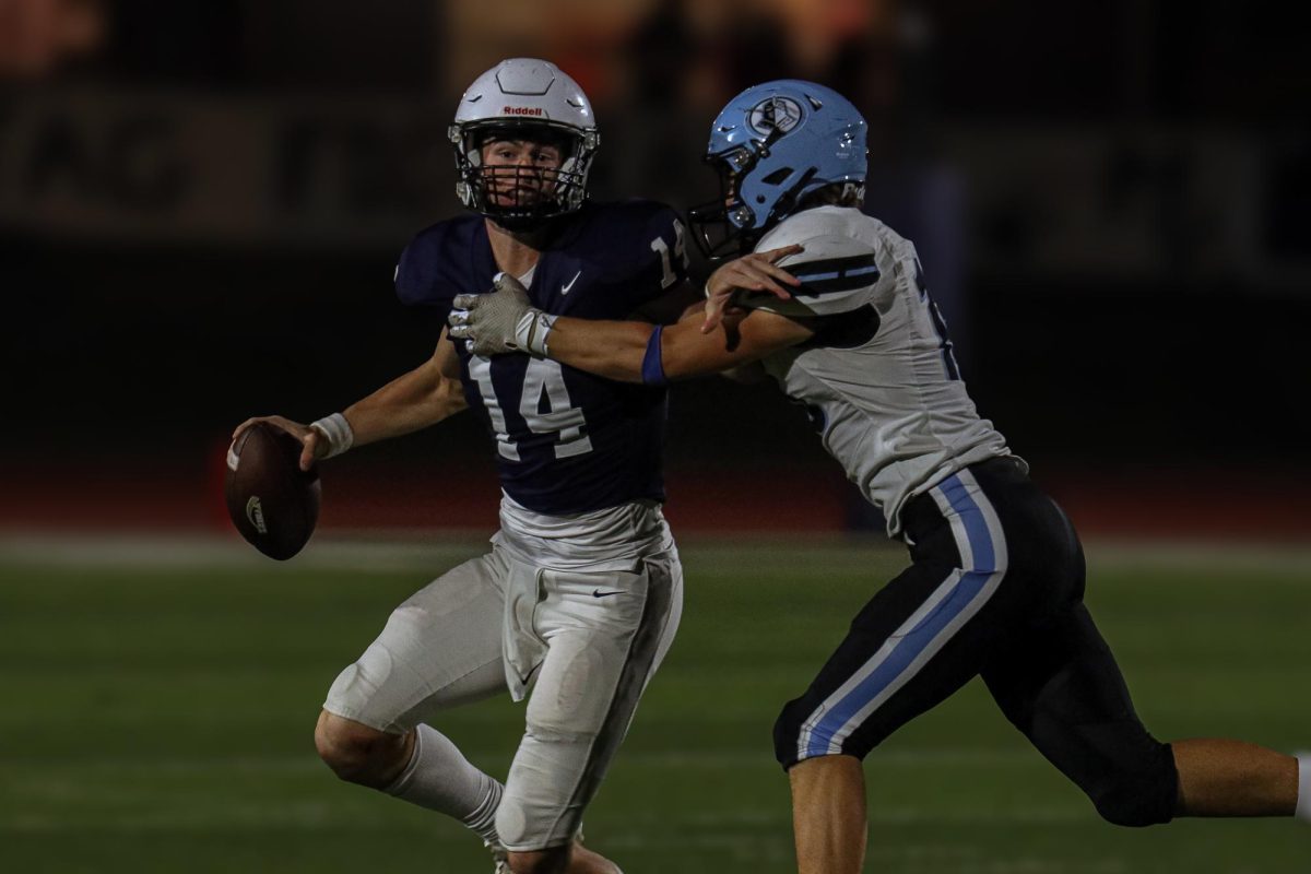 Protecting the ball, junior Connor Bohon looks down field for the receivers.