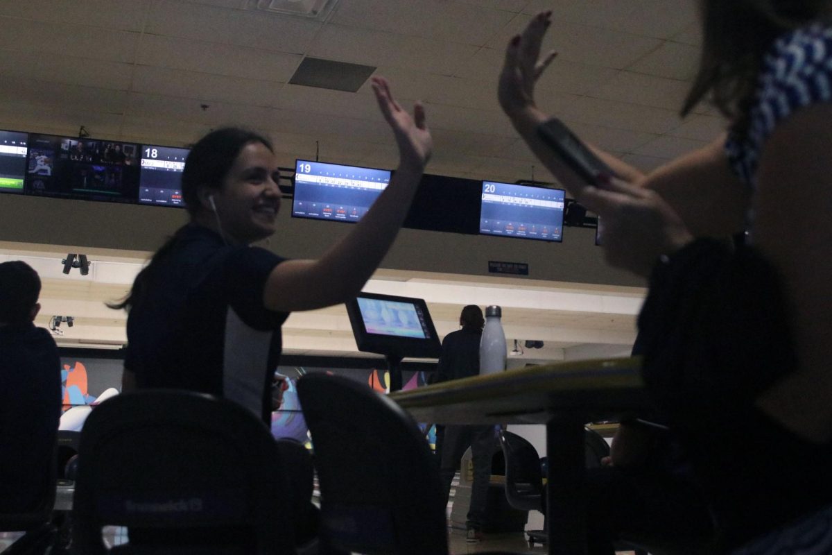 After bowling a strike, senior Sireen Fraitekh high fives her coach.