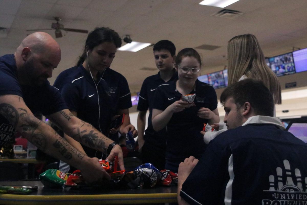 Meeting around the table, the unified bowling team grabs snacks. 