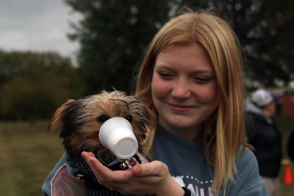 Laughing, junior Hailey Perrin holds her dog while they enjoy a pup cup. 