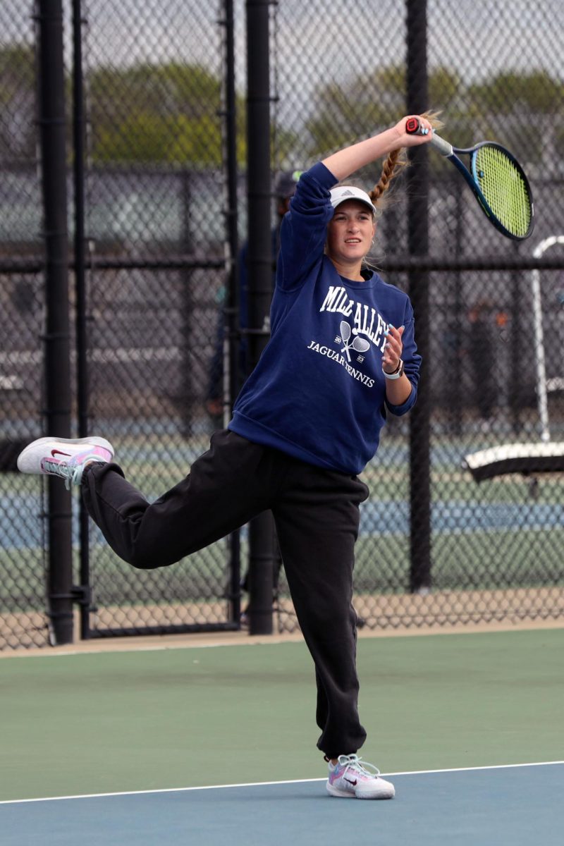 Arm above her head, junior Stella Platt follows through after hitting the ball. 
