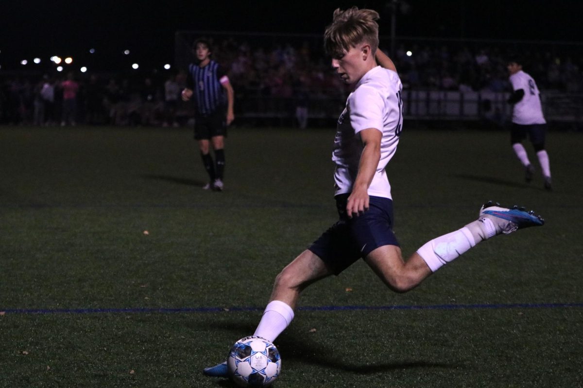 Leg in the air, junior Drew Enloe kicks the ball towards the goal. 
