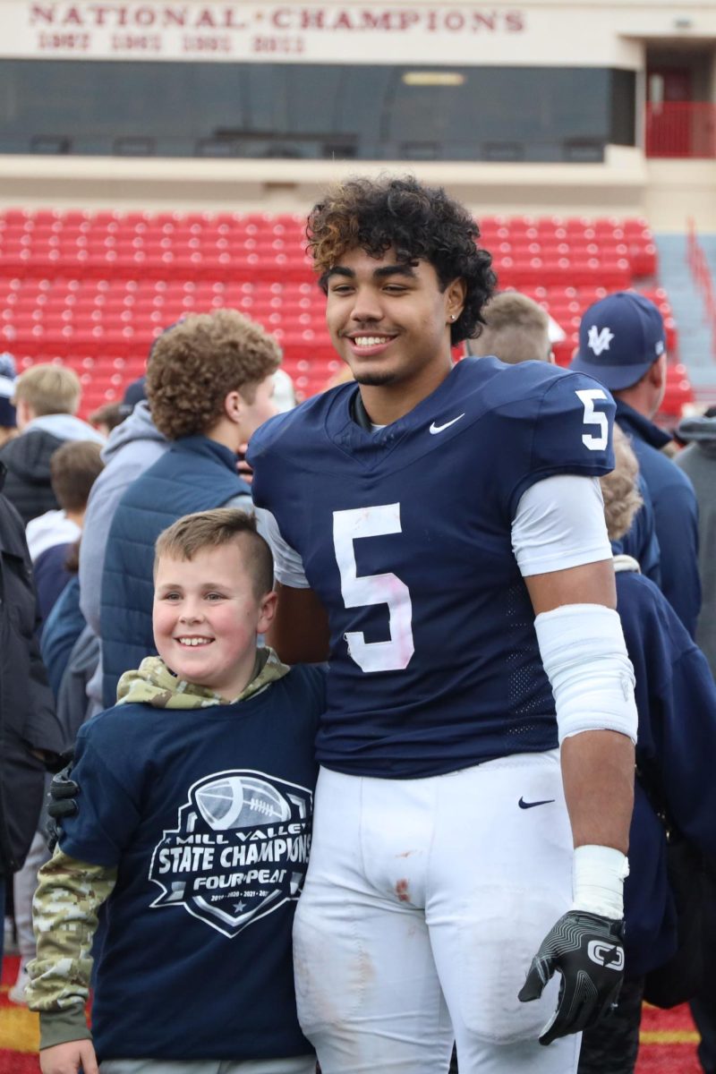 Junior Jayden Woods poses for a picture with a young fan.