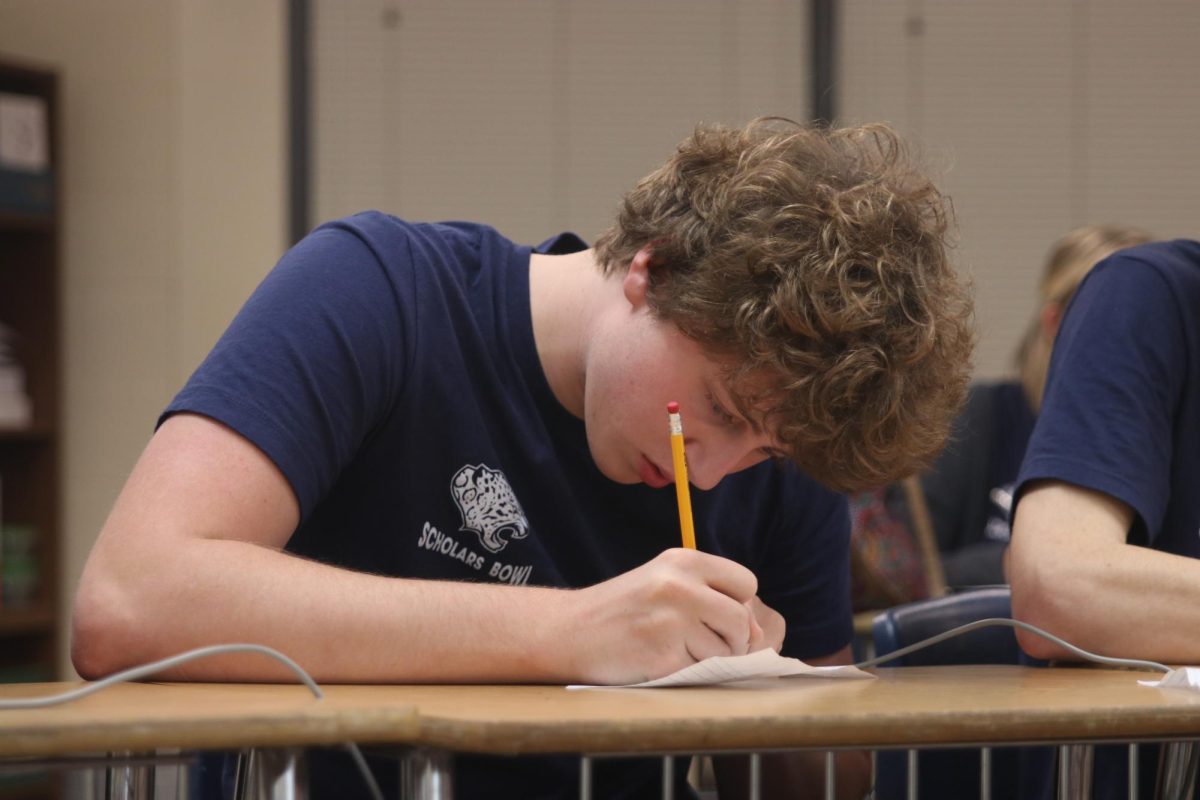 Focusing on his paper, junior Carter Tollman solves a math problem.
