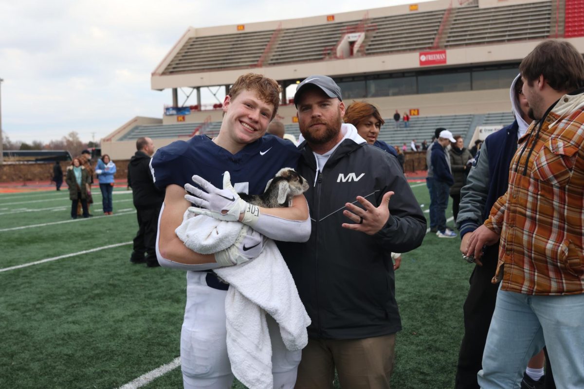 With a baby goat in his hands, senior Garrett Cronin and coach Matt Best celebrate the victory. 