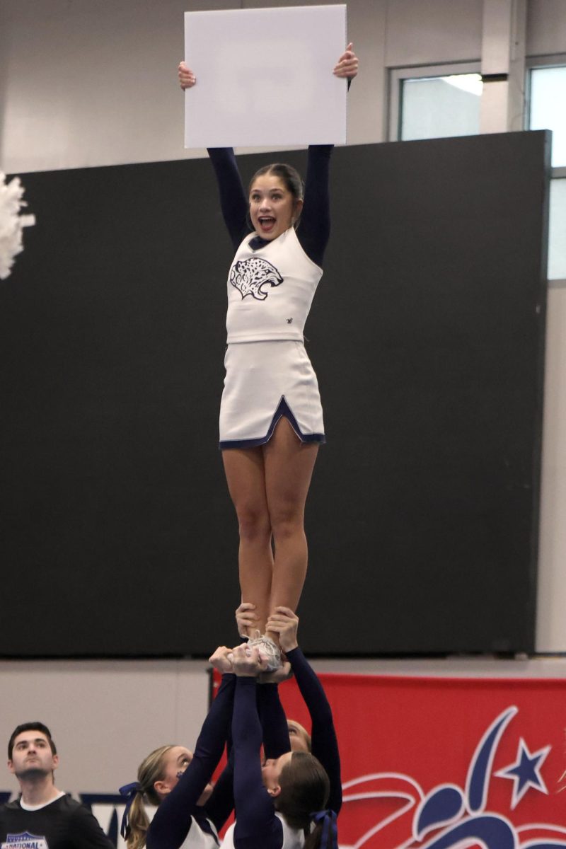 While in a stunt, junior Emersyn Jones holds up a white sign. 
