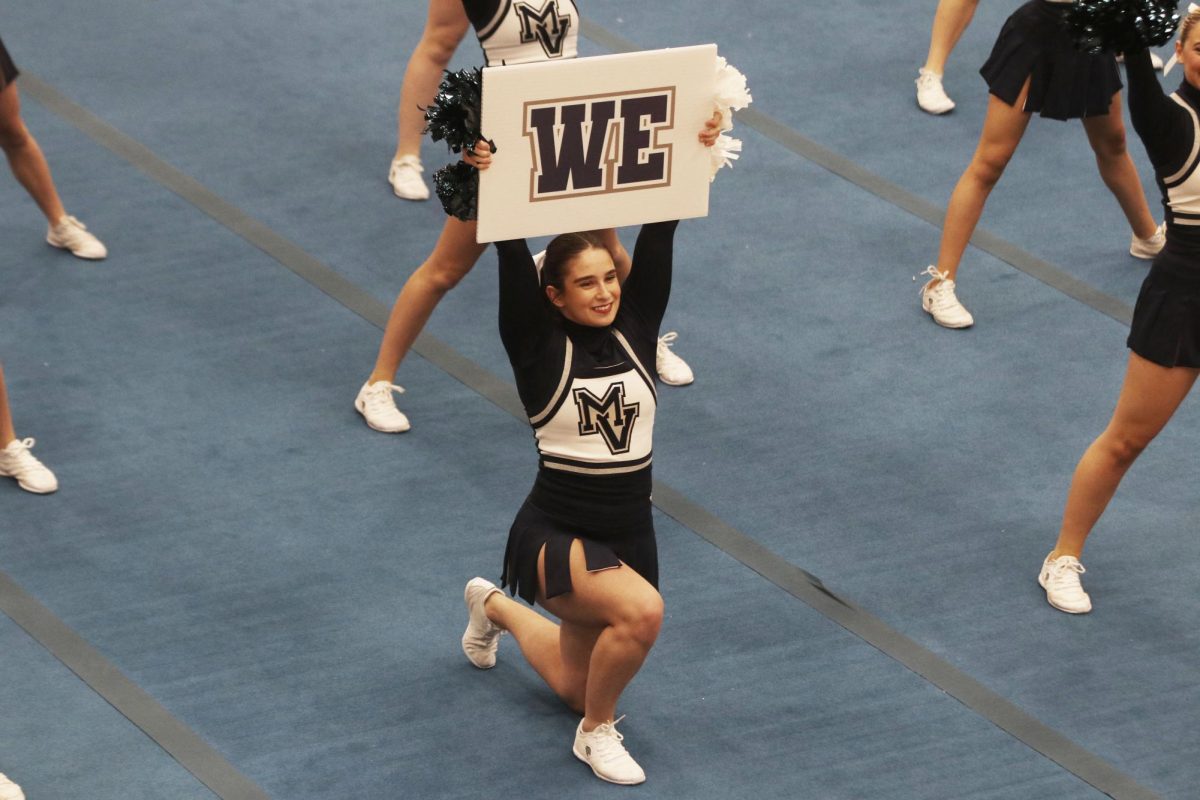 Smiling to the crowd, senior Makenna Payne holds up the we sign.