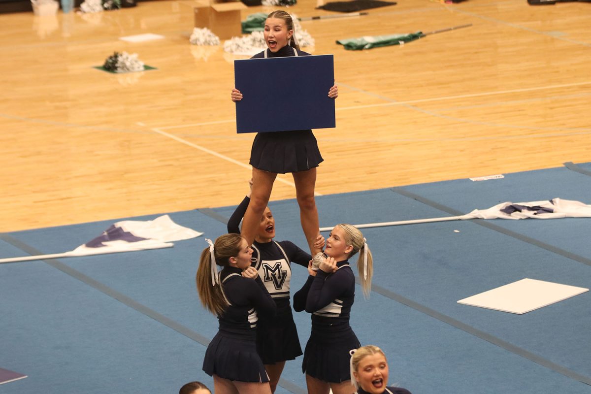 Yelling her chant, sophomore Sydney Epperson is held up by her bases.