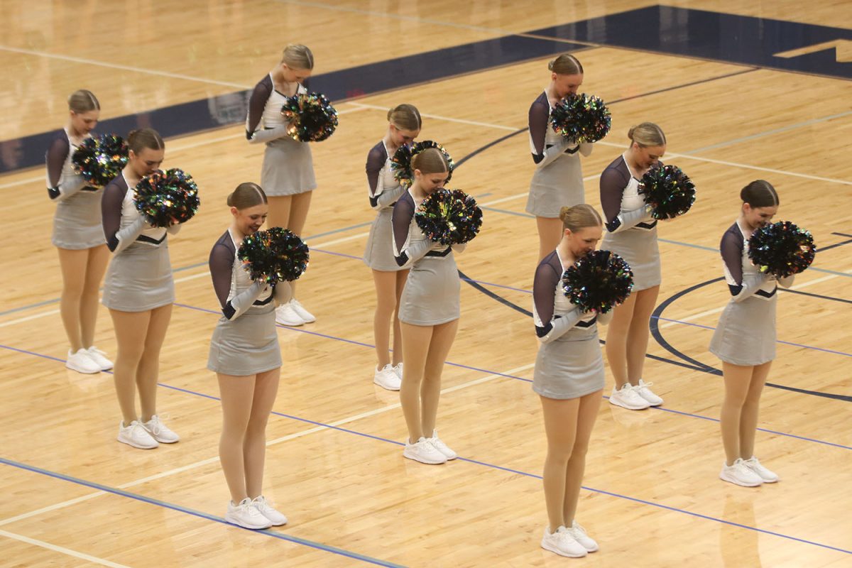 Waiting for their queue, the dance team hides their smiles behind their pom poms.