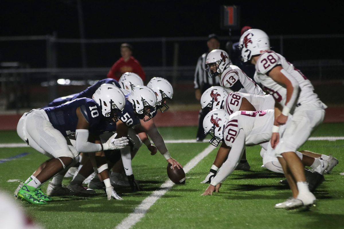 On the line of scrimmage, the team gets ready for the play to be called.