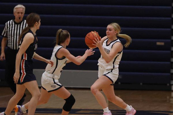 Catching the ball, freshman Riley Riggs goes to make a basket.