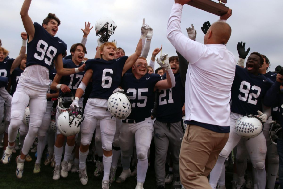 Coach Joel Applebee lifts the trophy and celebrates with the team. 