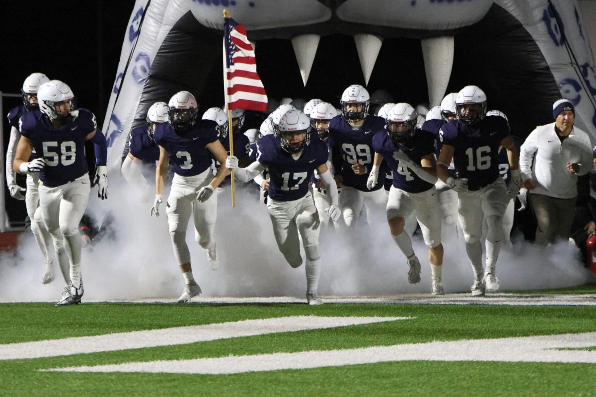 Senior Haden Applebee leads the team out of the jaguar head while Metallicas Enter Sandman plays over the speakers.