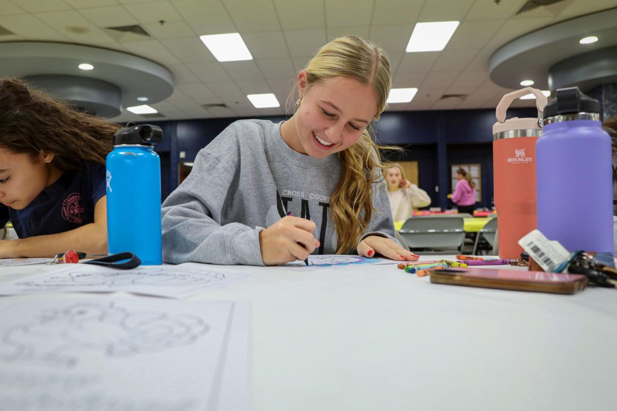Smiling, junior Maggie Wieland colors her turkey coloring sheet.