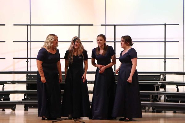 Singing as part of the girls quartet, seniors McKinley Graves, Violet Hentges, Grace Cormany and Sarah Coleman perform at the choir concert Wednesday, Oct. 25. All four members of the quartet were given positions on ECKMEA district choirs.